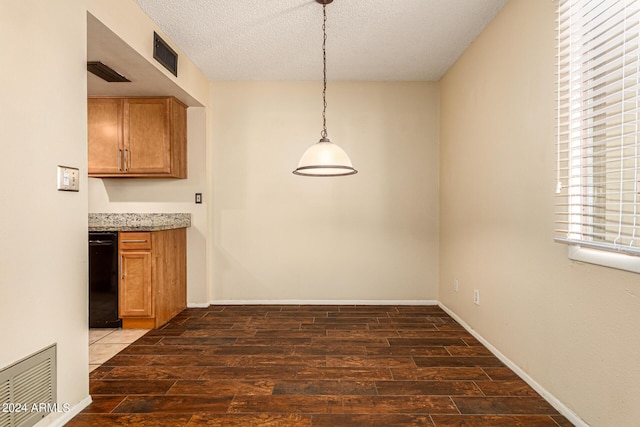 unfurnished dining area featuring baseboards, a textured ceiling, visible vents, and wood finished floors