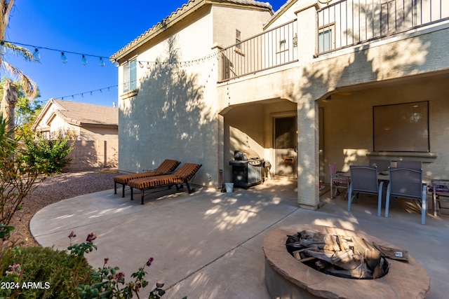 view of patio with a balcony, a grill, and an outdoor fire pit