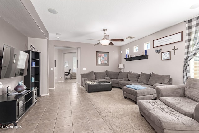 living room featuring a textured ceiling, light tile patterned floors, and ceiling fan