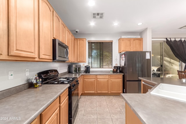 kitchen featuring light brown cabinets, stainless steel appliances, light tile patterned flooring, and sink