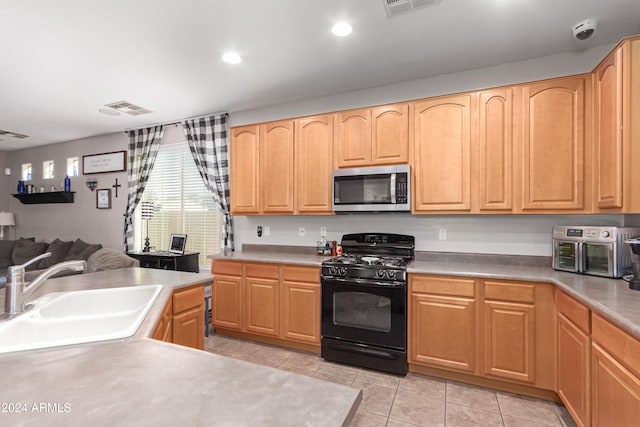 kitchen featuring light brown cabinets, light tile patterned flooring, black range with gas cooktop, and sink