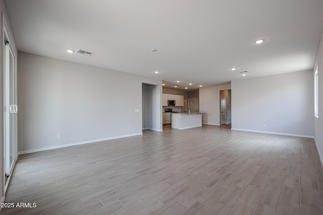 unfurnished living room featuring recessed lighting, baseboards, visible vents, and light wood-style flooring