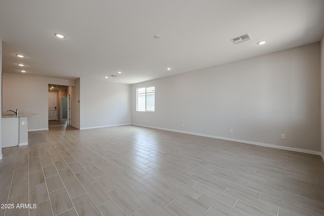 empty room with recessed lighting, baseboards, visible vents, and light wood-type flooring