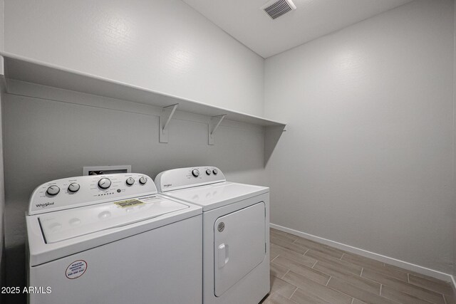 laundry area featuring wood tiled floor, laundry area, visible vents, baseboards, and separate washer and dryer