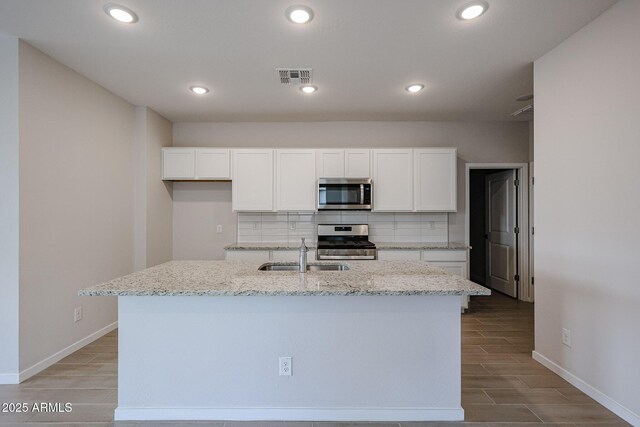 kitchen with white cabinets, a sink, stainless steel appliances, decorative backsplash, and visible vents
