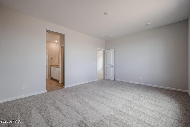 unfurnished bedroom with baseboards, visible vents, light carpet, and ensuite bathroom
