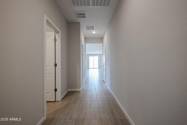 hall with baseboards, light wood-type flooring, and visible vents