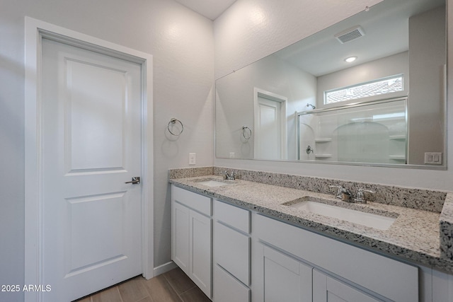 full bathroom with a sink, a stall shower, double vanity, and visible vents
