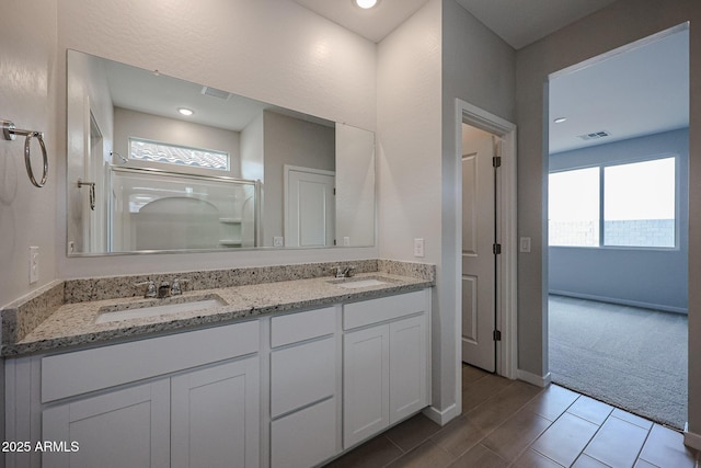 full bathroom featuring visible vents, a sink, a stall shower, and double vanity