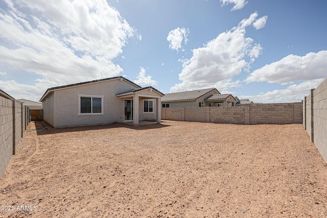 back of house with a fenced backyard and stucco siding