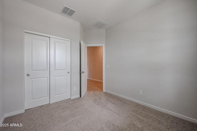 unfurnished bedroom featuring carpet floors, baseboards, a closet, and visible vents
