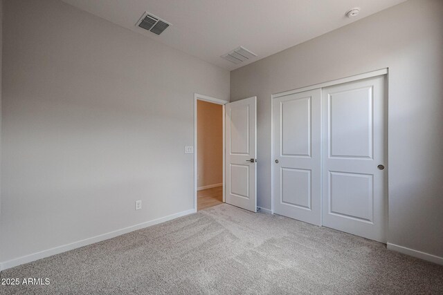 unfurnished bedroom featuring baseboards, carpet, a closet, and visible vents