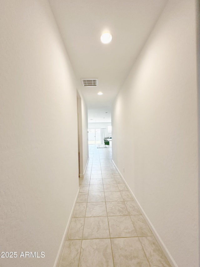 corridor with light tile patterned floors, visible vents, and baseboards