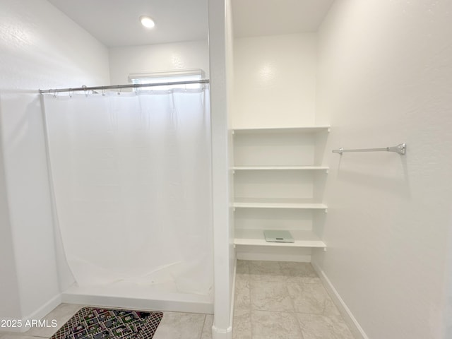 bathroom featuring curtained shower and baseboards