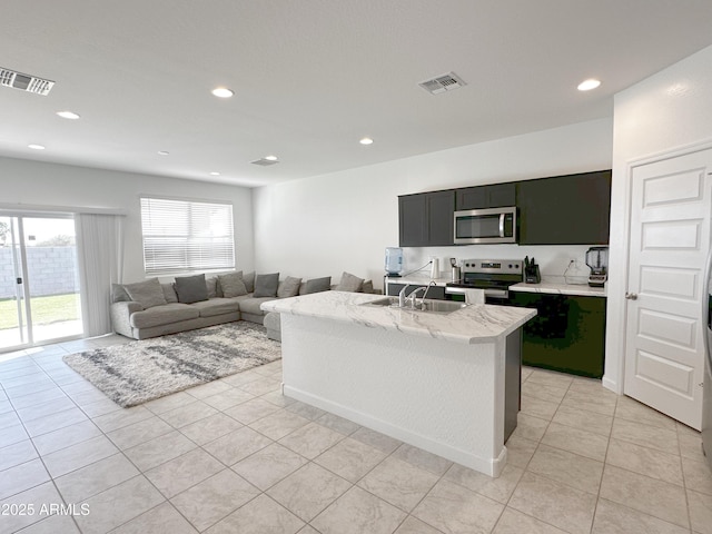 kitchen featuring stainless steel appliances, a sink, visible vents, and dark cabinets