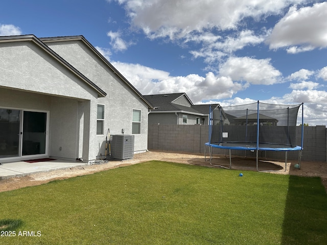 view of yard featuring central air condition unit, a trampoline, and fence