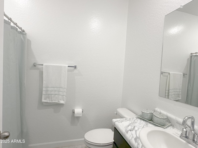 bathroom featuring toilet, baseboards, and vanity