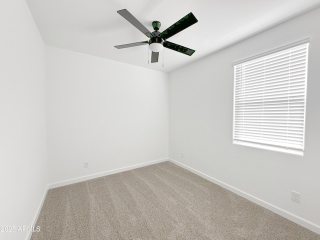 carpeted spare room featuring ceiling fan and baseboards