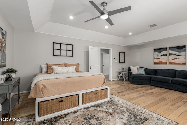 bedroom with visible vents, hardwood / wood-style flooring, baseboards, recessed lighting, and a raised ceiling