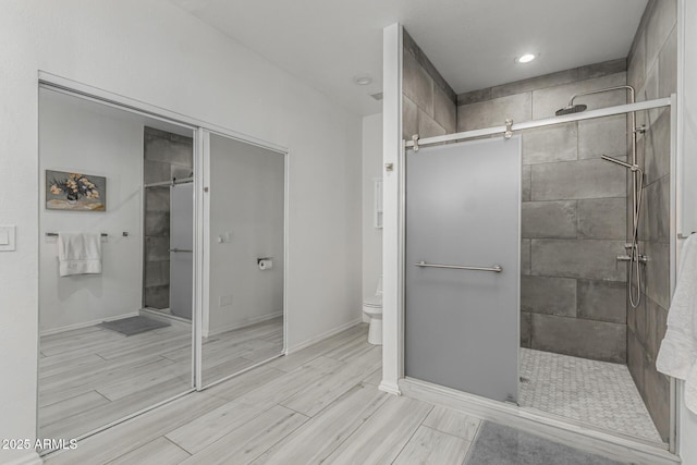 full bathroom featuring wood finish floors, toilet, and a stall shower