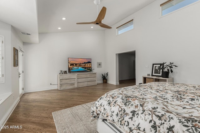 bedroom with wood finished floors, baseboards, visible vents, a towering ceiling, and recessed lighting