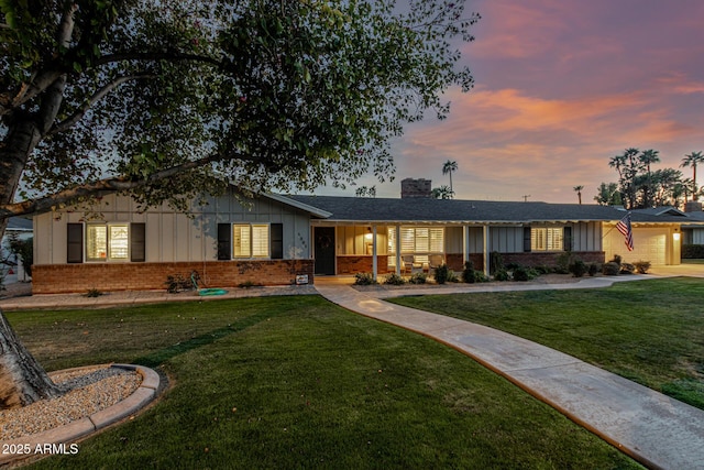 ranch-style house with brick siding, a chimney, a front lawn, and board and batten siding