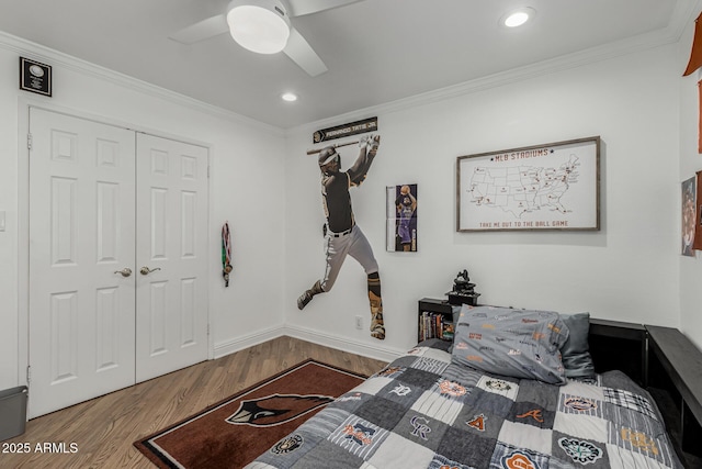 bedroom with a closet, ceiling fan, wood finished floors, and crown molding