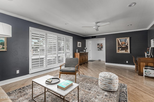 living room with baseboards, ceiling fan, wood finished floors, and crown molding