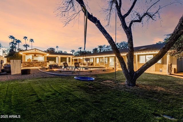 back of property at dusk with an outdoor pool, a lawn, stucco siding, and a patio area