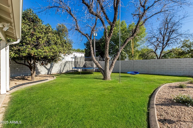 view of yard with a trampoline and a fenced backyard