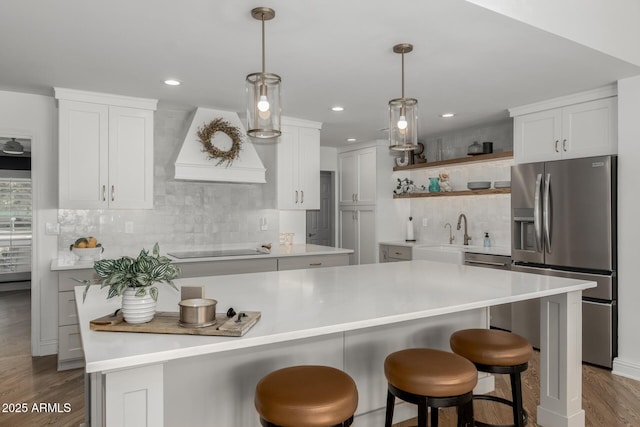 kitchen with a sink, open shelves, stainless steel fridge with ice dispenser, premium range hood, and black electric stovetop