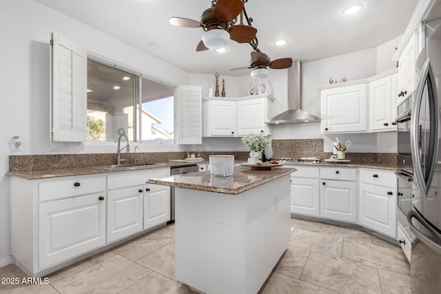 kitchen featuring white cabinetry, sink, a kitchen island, dark stone counters, and wall chimney exhaust hood