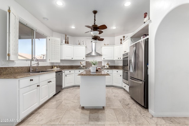 kitchen featuring sink, wall chimney exhaust hood, white cabinets, a kitchen island, and stainless steel appliances