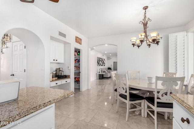 dining room with ceiling fan with notable chandelier