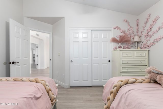 bedroom with a closet, light wood-type flooring, and vaulted ceiling