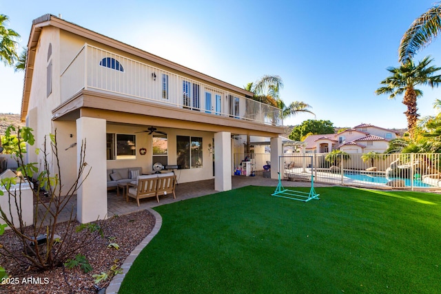 back of property with ceiling fan, a balcony, outdoor lounge area, a fenced in pool, and a patio area