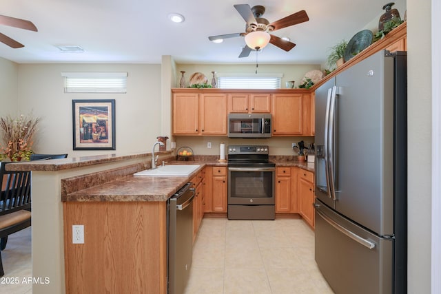 kitchen with appliances with stainless steel finishes, kitchen peninsula, sink, and a wealth of natural light