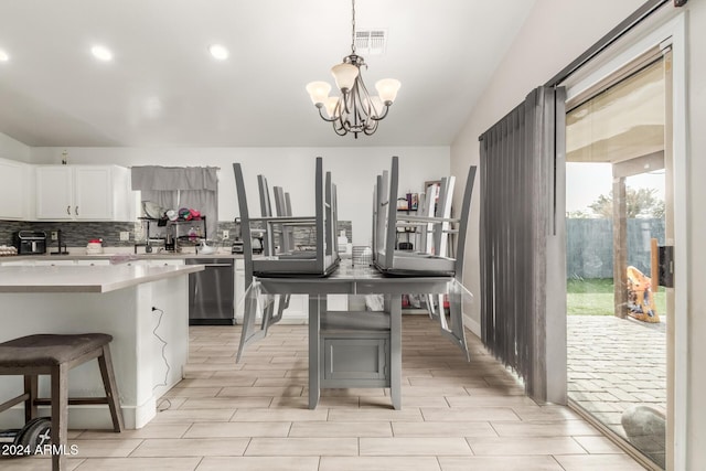 kitchen featuring white cabinets, a chandelier, stainless steel dishwasher, and a breakfast bar area