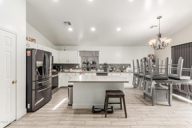 kitchen with decorative backsplash, appliances with stainless steel finishes, a kitchen breakfast bar, white cabinets, and a center island