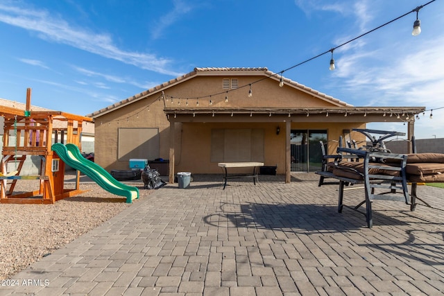 rear view of property with a patio area and a playground