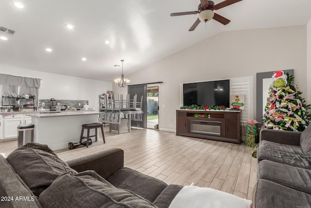 living room with ceiling fan with notable chandelier and lofted ceiling