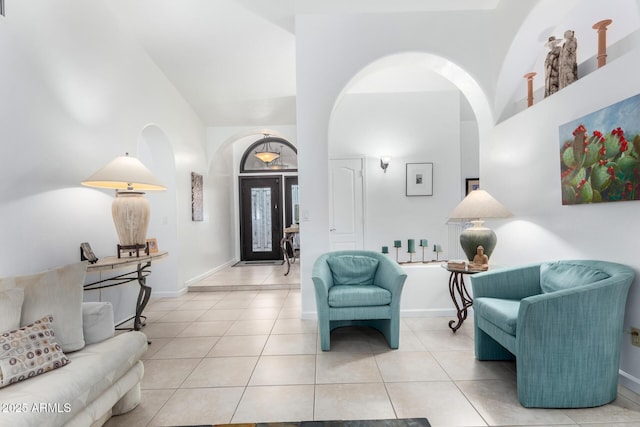 foyer entrance with a high ceiling, light tile patterned flooring, and baseboards