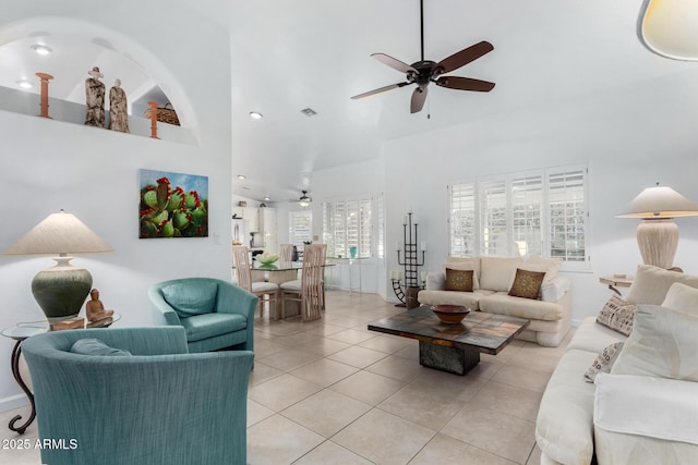 living area with light tile patterned floors, a high ceiling, visible vents, and a ceiling fan