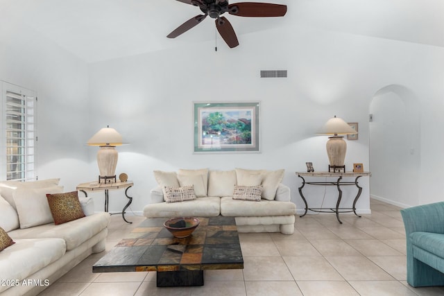 tiled living room with arched walkways, visible vents, vaulted ceiling, ceiling fan, and baseboards