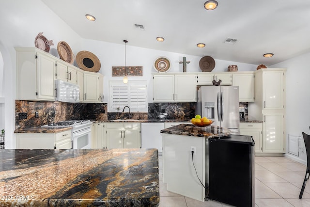 kitchen with white appliances, visible vents, a center island, vaulted ceiling, and a sink