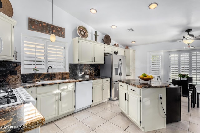 kitchen with light tile patterned floors, a sink, visible vents, vaulted ceiling, and dishwasher