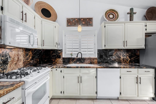 kitchen featuring white appliances, dark stone countertops, white cabinets, and a sink