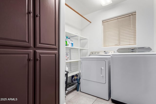 laundry room featuring light tile patterned floors, separate washer and dryer, and cabinet space