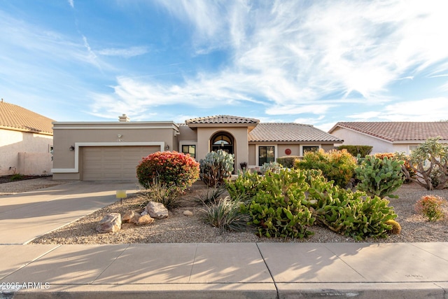 mediterranean / spanish-style home with a garage, a tiled roof, concrete driveway, and stucco siding