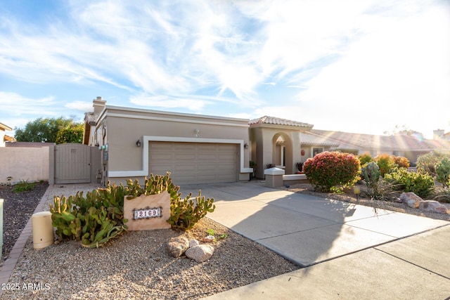 mediterranean / spanish house with a garage, a gate, concrete driveway, and stucco siding